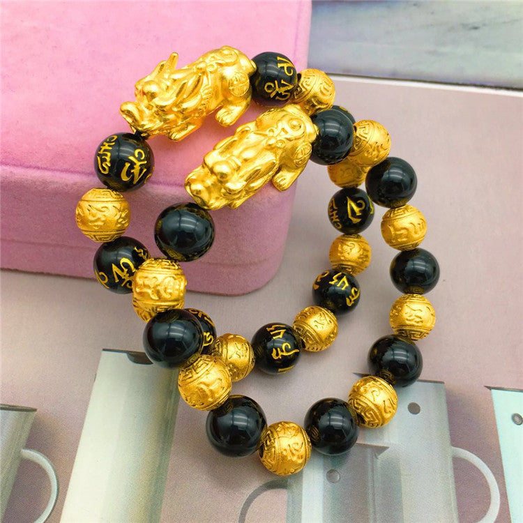 Trendy gold bracelet featuring black beads and intricate gold details for a stylish look