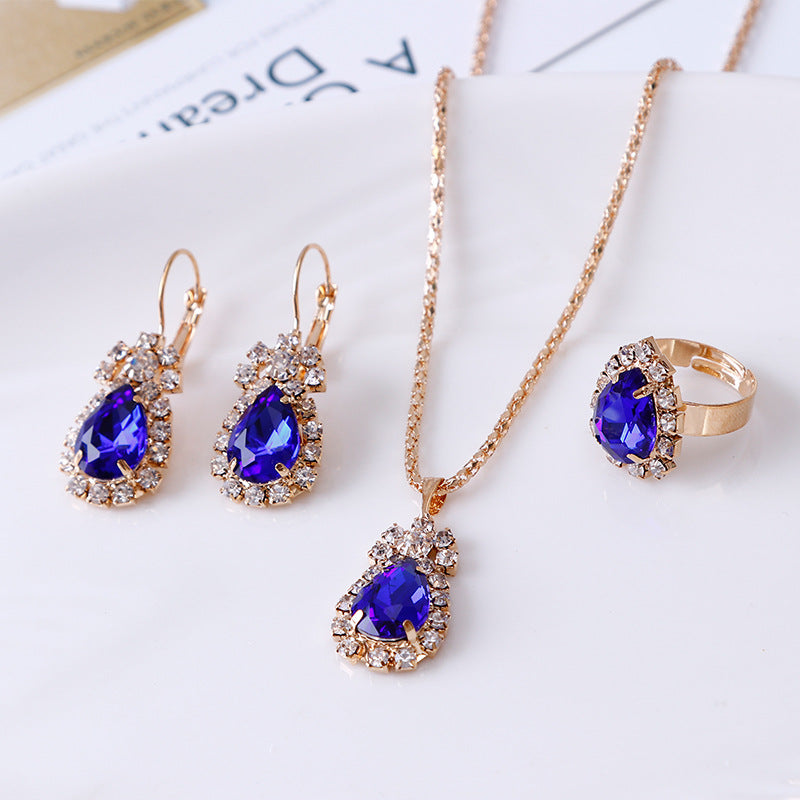 Elegant rhinestone jewelry set featuring a necklace, earrings, and ring with blue gemstones