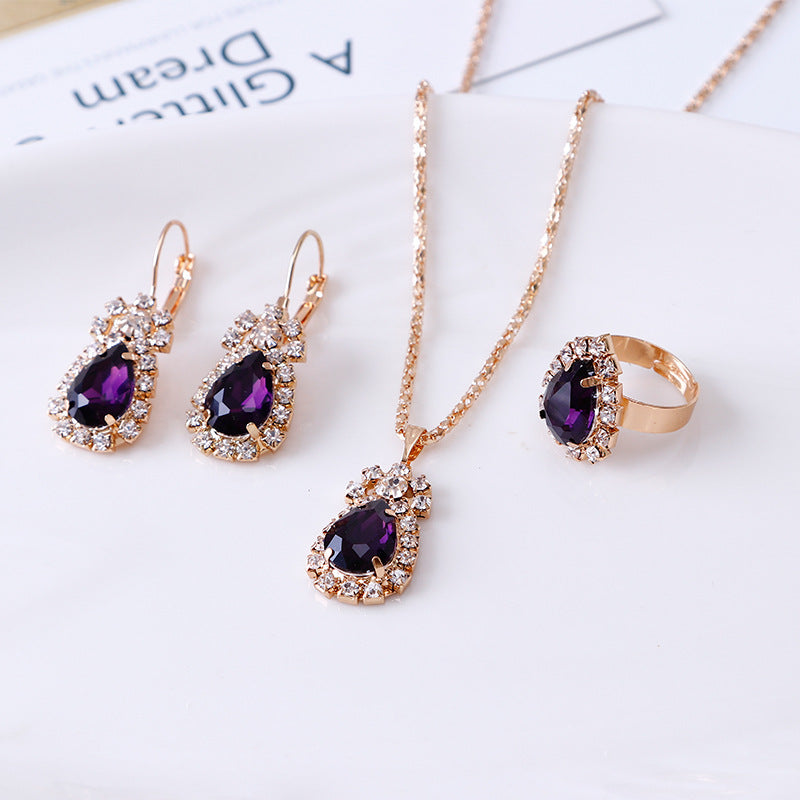 Elegant rhinestone jewelry set featuring a necklace, earrings, and ring with purple gemstones