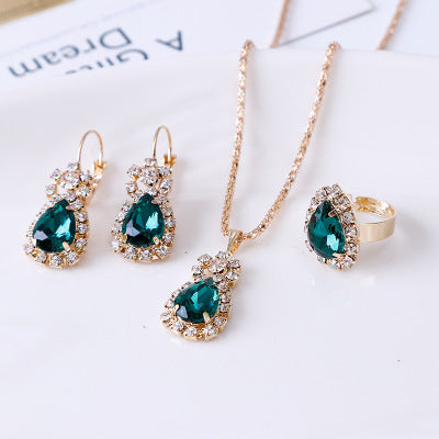 Rhinestone jewelry set featuring a necklace, earrings, and ring with emerald and gold accents