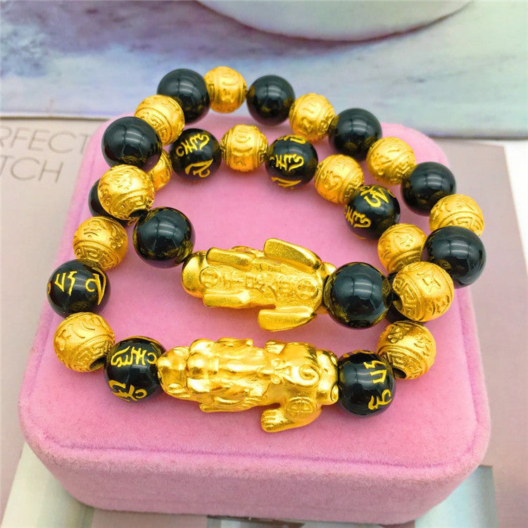 Trendy gold bracelet featuring black beads and intricate golden Buddhist lion design